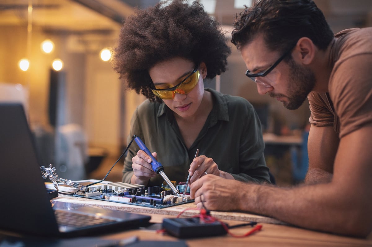 Woman soldering a circuit board in her office