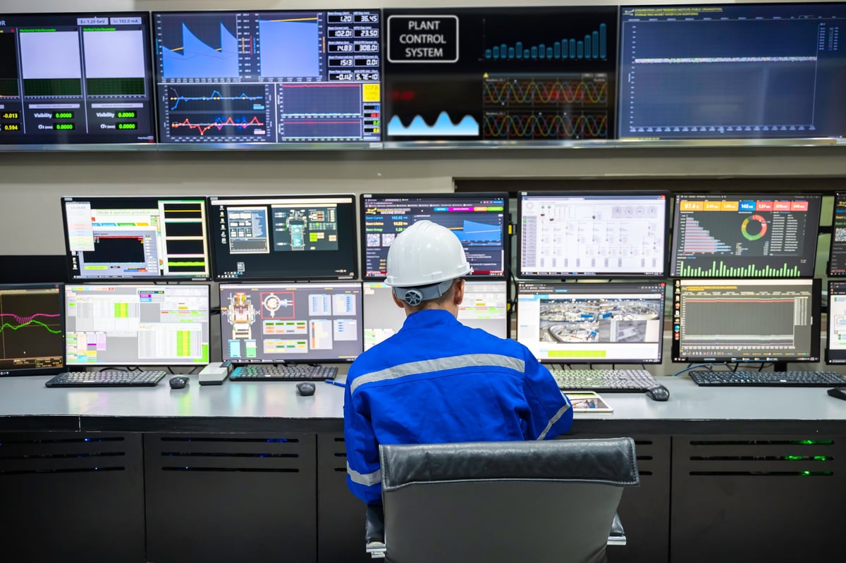 Engineer working at control room, monitoring dashboard screens and analytics.
