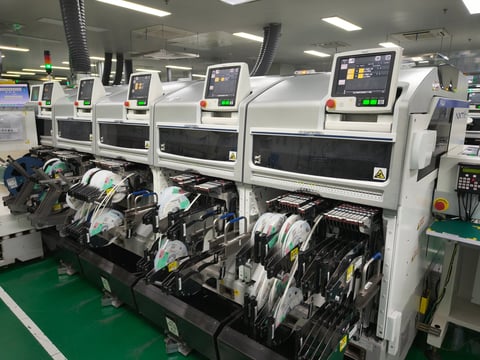 Industrial manufacturing equipment with multiple white machines processing circuit boards in a factory production line